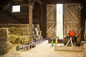 14384517-Interior-of-wooden-barn-with-hay-bales-stacks-and-farm-equipment-Stock-Photo